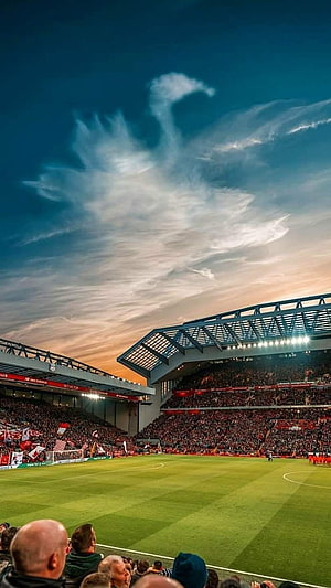 Stunning sunset view of a packed football stadium with dramatic clouds and cheering fans HD phone wallpaper