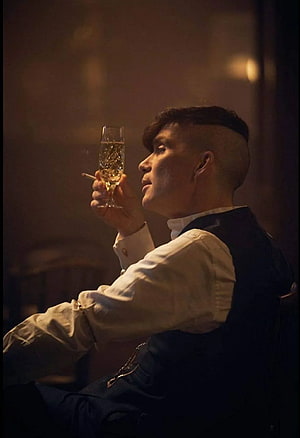 Thomas Shelby in a dimly lit room holding a champagne glass and cigarette HD phone wallpaper