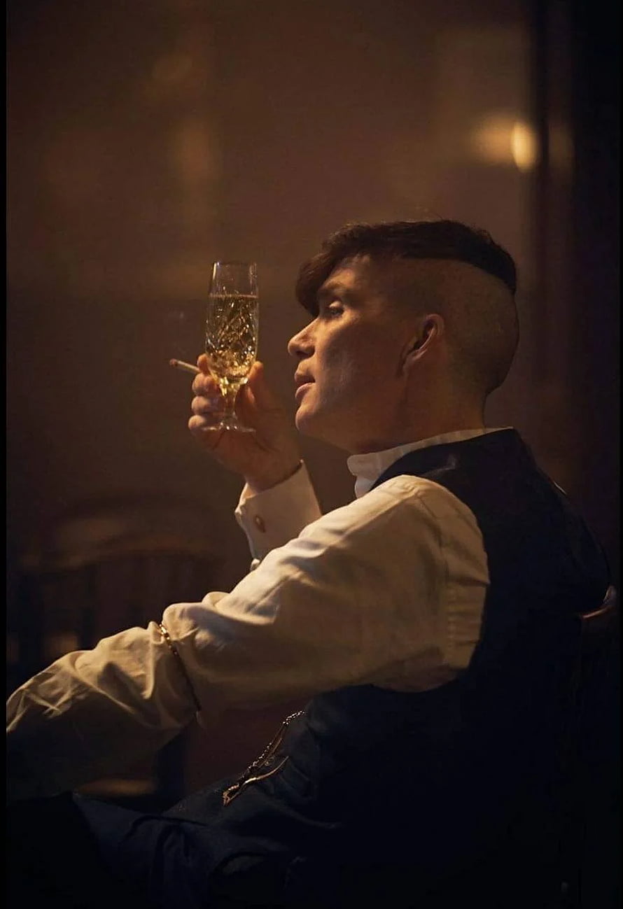 Thomas Shelby in a dimly lit room holding a champagne glass and cigarette HD phone wallpaper