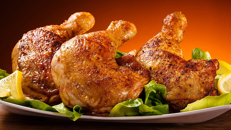 Golden Roast Chicken Legs on a Bed of Fresh Lettuce with Lemon Wedges HD wallpaper