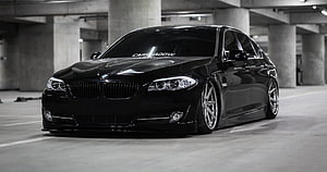 Black BMW F10 5 Series Sedan in Concrete Parking Garage HD wallpaper