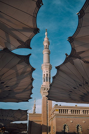Majestic Mosque Minaret Framed by Decorative Umbrellas Against Blue Sky HD phone wallpaper