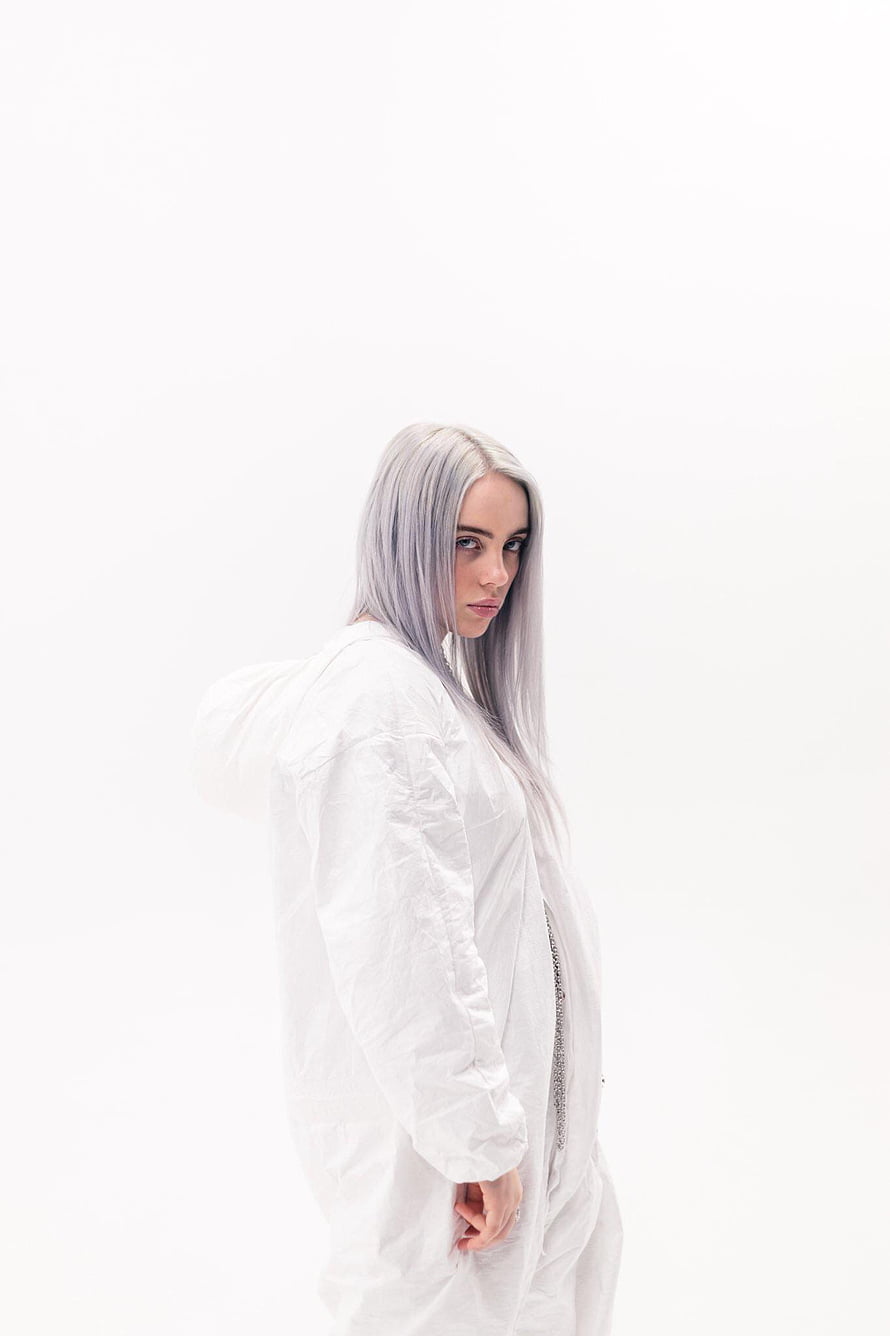 Billie Eilish in a white hooded outfit with silver hair against a plain white background HD phone wallpaper