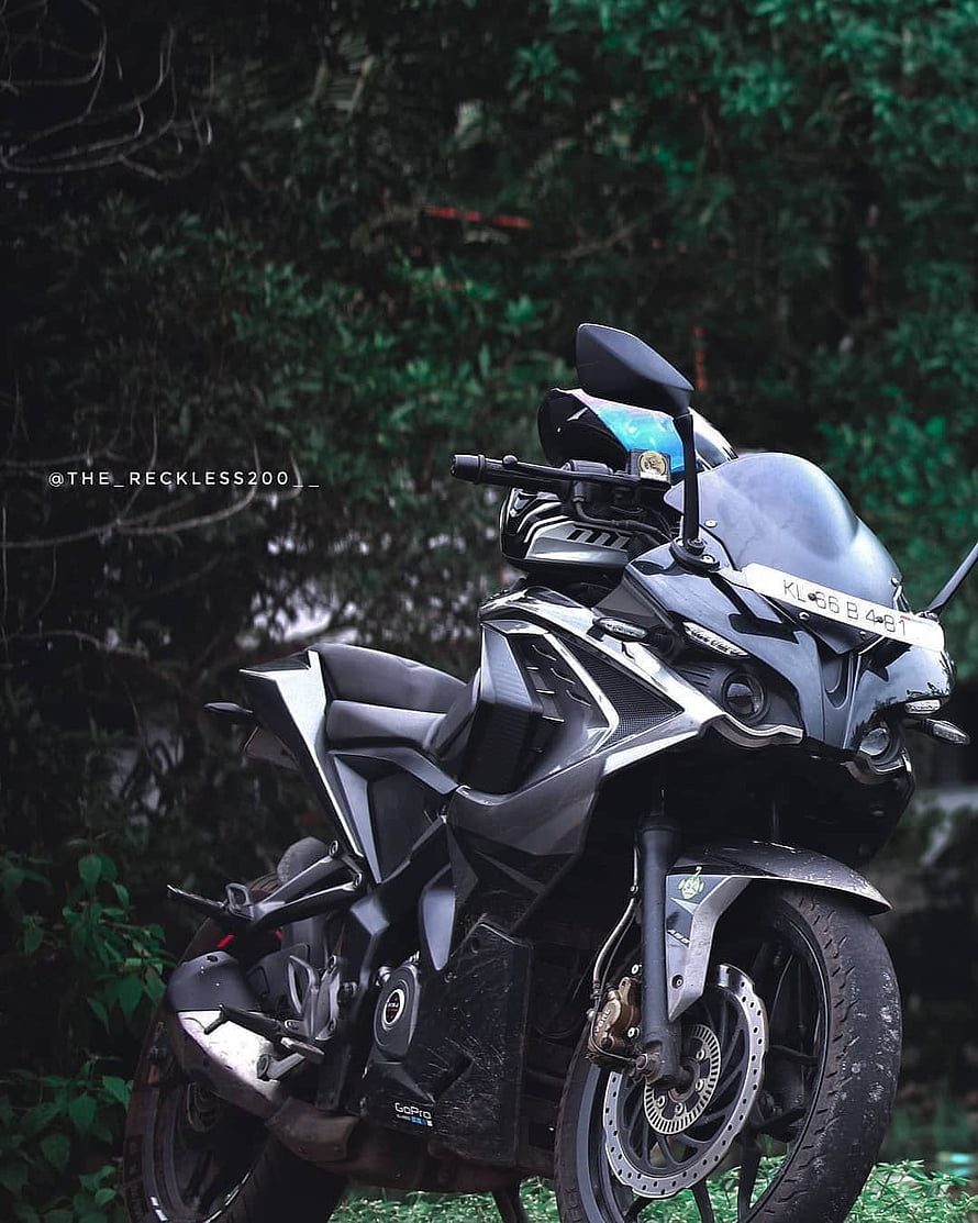 Bajaj Pulsar RS 200 sport motorcycle parked in a lush green forest setting HD phone wallpaper