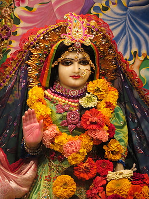 Srimati Radharani adorned in vibrant floral garlands and ornate golden jewelry HD phone wallpaper