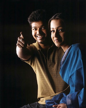 Vishal and Trisha Krishnan smiling portrait with pointing gesture in warm lighting HD phone wallpaper