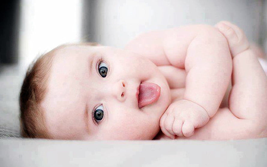 Adorable Baby Lying Down With Tongue Out And Big Blue Eyes HD wallpaper