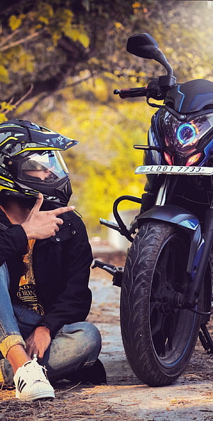 Biker in Helmet Pointing at Black Motorcycle with Blue Accents HD phone wallpaper