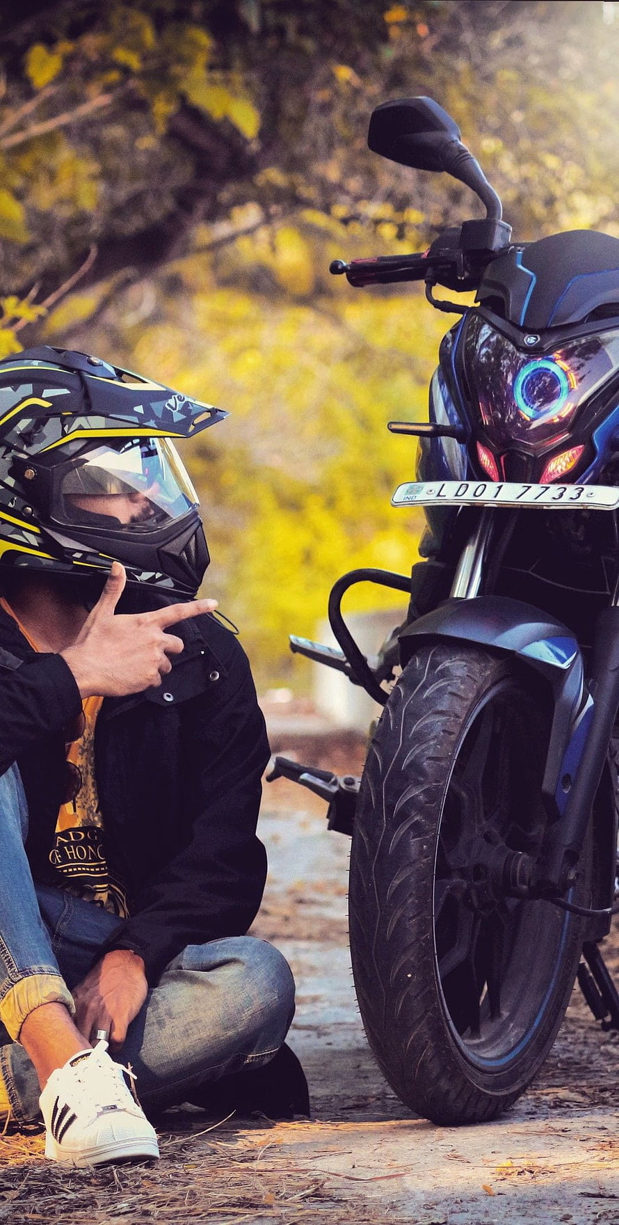 Biker in Helmet Pointing at Black Motorcycle with Blue Accents HD phone wallpaper