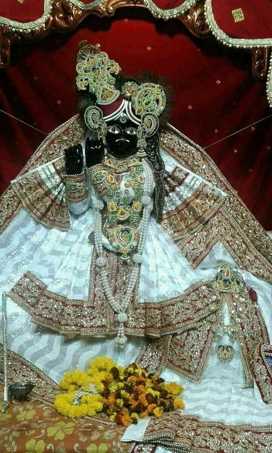 Banke Bihari Krishna Murti in Ornate Temple Attire with Marigold Offerings HD phone wallpaper