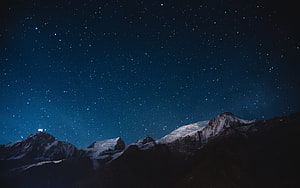 Snow-Capped Mountain Range Under a Deep Blue Starry Night Sky HD wallpaper