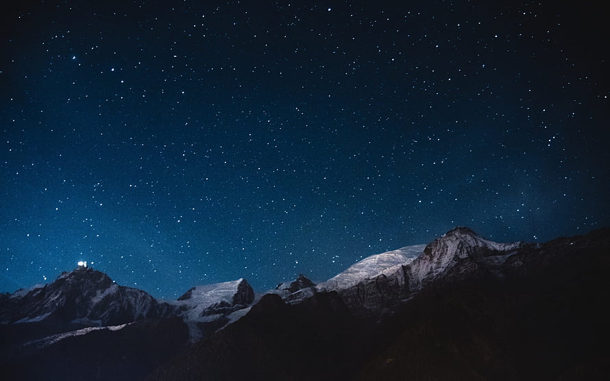 Snow-Capped Mountain Range Under a Deep Blue Starry Night Sky HD wallpaper
