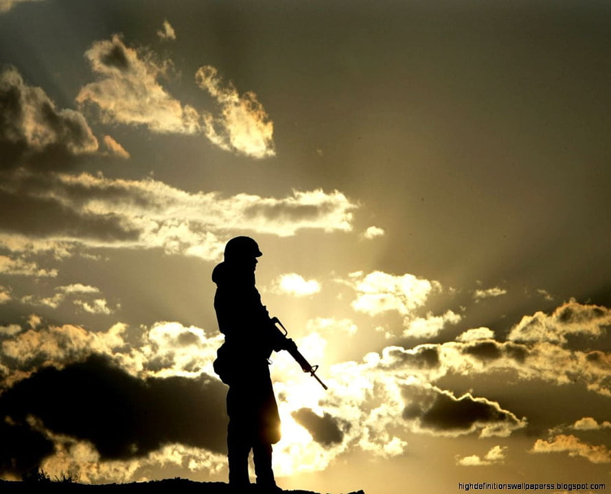 Silhouette of a soldier standing on a hilltop against a dramatic sunset sky with clouds HD wallpaper