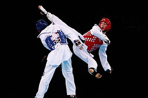 Taekwondo Athletes in Dynamic Sparring Match with Protective Gear HD wallpaper
