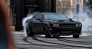 Black Dodge Challenger SRT Demon performing a burnout on an urban street with tire smoke HD wallpaper