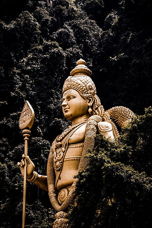 Golden Murugan Statue at Batu Caves Surrounded by Lush Greenery HD phone wallpaper
