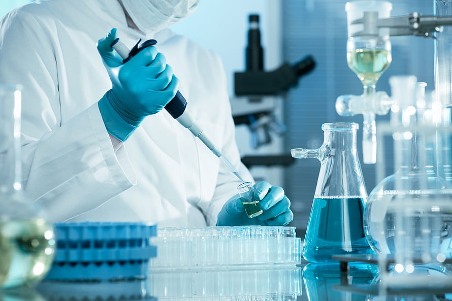 Scientist in white coat using pipette in a modern chemistry laboratory with glassware and microscope HD wallpaper