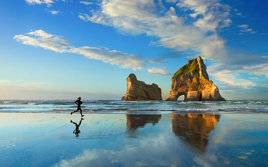 Runner on Wet Sand with Sea Stacks and Reflections at Golden Hour HD wallpaper