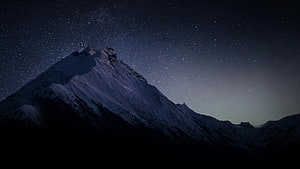 Snow-Capped Mountain Peak Under a Starry Night Sky HD wallpaper