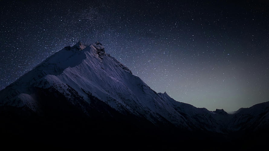 Snow-Capped Mountain Peak Under a Starry Night Sky HD wallpaper
