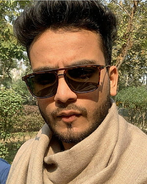 Elvish Yadav Wearing Tortoiseshell Sunglasses and Beige Shawl in a Green Park HD phone wallpaper