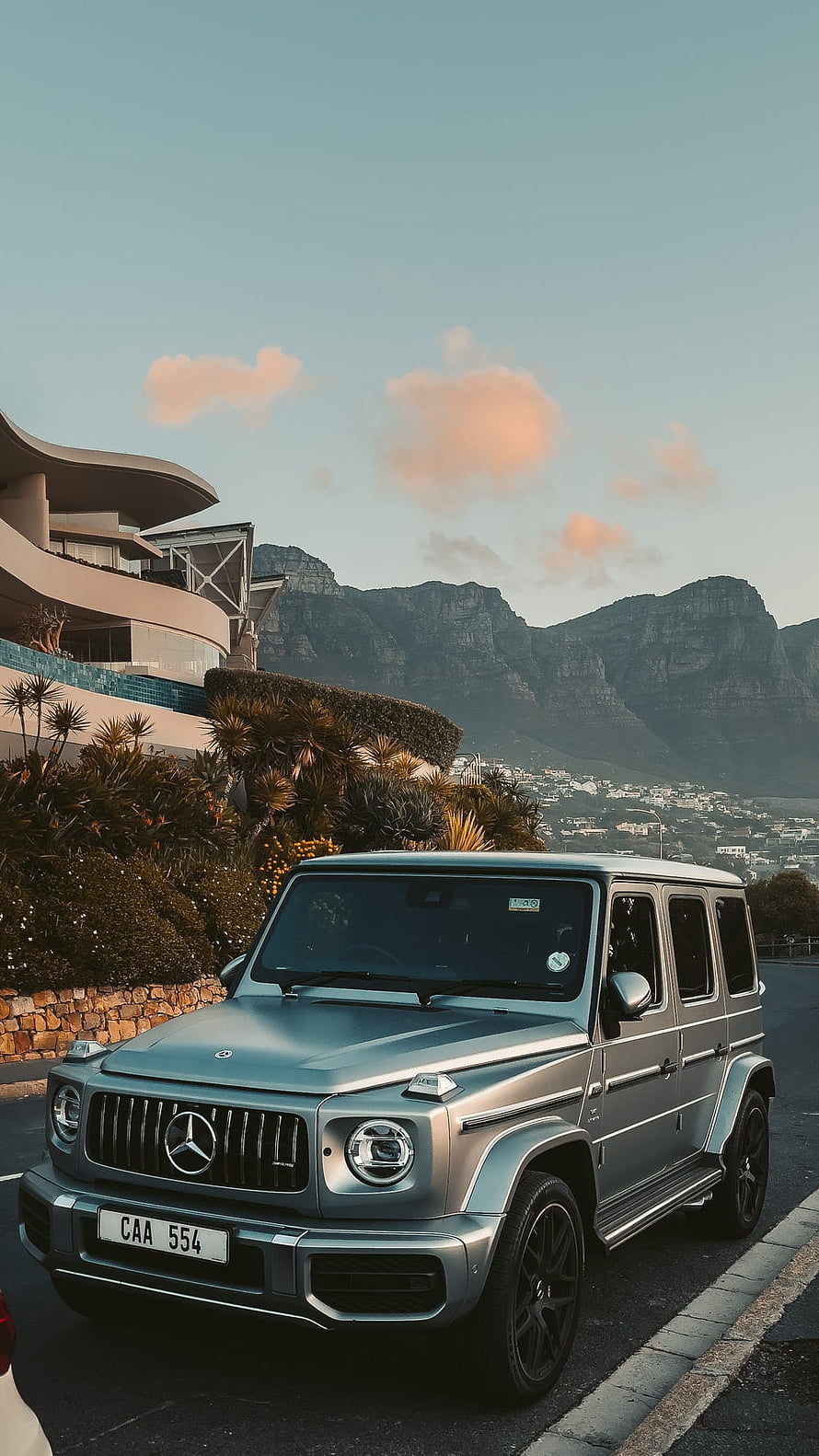 Silver Mercedes-AMG G63 Wagon Parked on a Scenic Coastal Road with Mountain Backdrop HD phone wallpaper