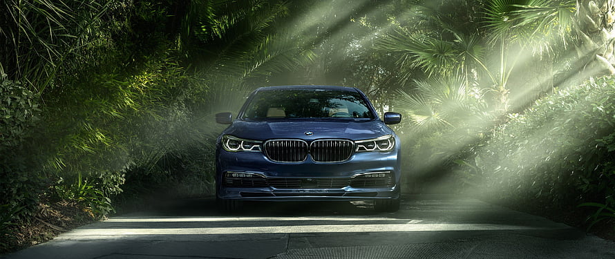 Blue BMW 7 Series Sedan Parked on a Sunlit Tropical Road HD wallpaper