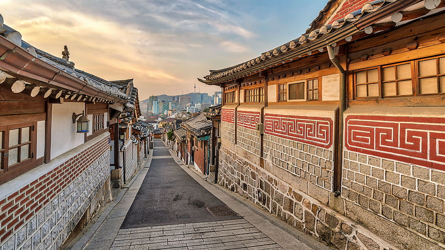 Traditional Hanok Alley in Seoul with City Skyline at Golden Hour HD wallpaper