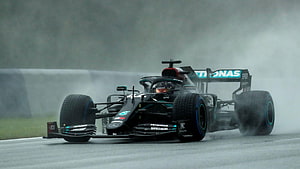 Lewis Hamilton Mercedes F1 car kicking up spray on a wet race track HD wallpaper