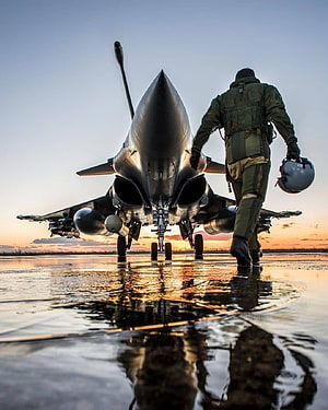 Fighter Pilot Walking Towards Jet on Wet Runway at Sunset HD phone wallpaper