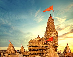Sunset view of the Khajuraho temples in India with orange flags fluttering against a dramatic sky HD wallpaper