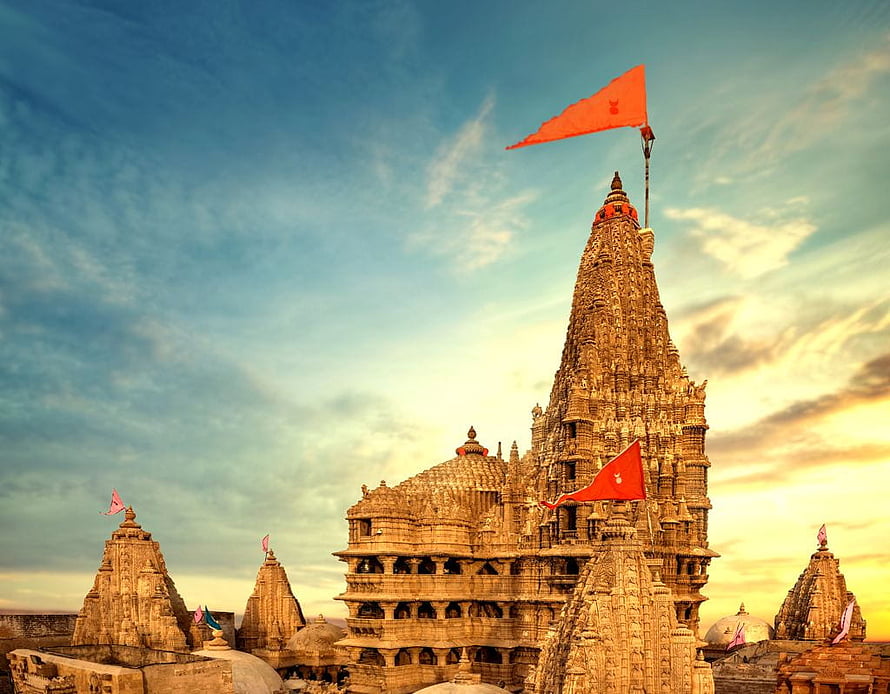 Sunset view of the Khajuraho temples in India with orange flags fluttering against a dramatic sky HD wallpaper