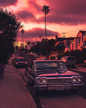 Vintage American Sedan Parked on a Residential Street Under a Dramatic Pink Sunset Sky HD phone wallpaper