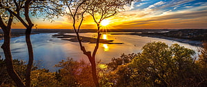 Golden sunset over a wide river with silhouetted trees and warm sky reflections HD wallpaper