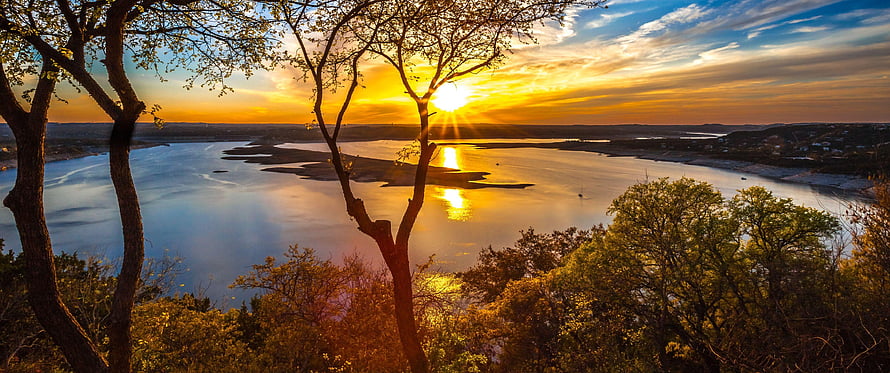 Golden sunset over a wide river with silhouetted trees and warm sky reflections HD wallpaper