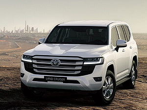White Toyota Land Cruiser 300 Series SUV Parked on Rocky Desert Terrain with City Skyline HD wallpaper
