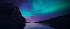 Vivid Green and Purple Aurora Borealis Over a Serene Mountain Lake at Night HD wallpaper