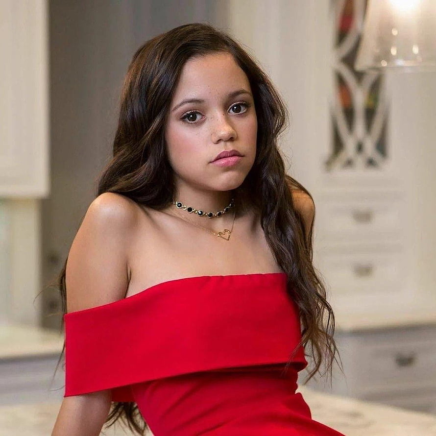 Jenna Ortega in a red off-shoulder dress with layered necklaces and long wavy hair HD phone wallpaper