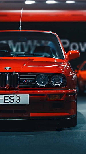 Front view of a classic red BMW M3 E30 sports car with iconic grille and headlights HD phone wallpaper