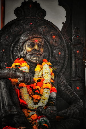 Statue of Chhatrapati Shivaji Maharaj adorned with marigold garlands and traditional attire HD phone wallpaper
