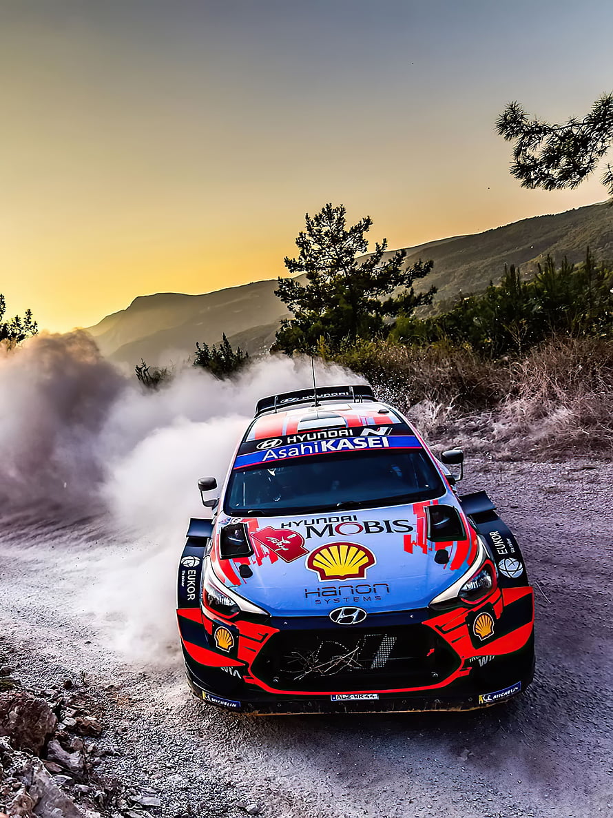 Hyundai i20 N Rally1 drifting on a dusty mountain road at sunset HD phone wallpaper