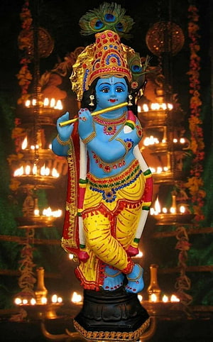 Lord Krishna Statue Playing Flute in Temple Setting with Oil Lamps HD phone wallpaper