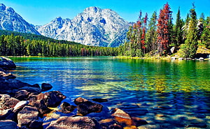 Serene Alpine Lake with Turquoise Waters, Rocky Shoreline, and Snow-Capped Mountain Peaks HD wallpaper