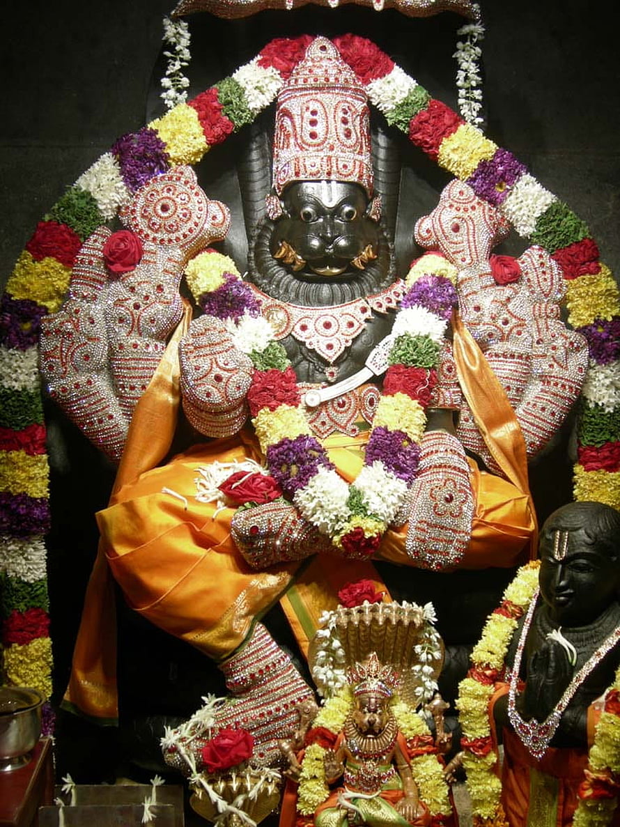 Ornate Narasimha Swamy Temple Idol Adorned With Vibrant Flower Garlands And Jewels HD phone wallpaper