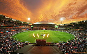 Vibrant Cricket Stadium at Sunset with Flaming Pyrotechnics and Full Crowd HD wallpaper