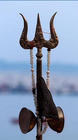 Ornate Mahadev Trishul with Rudraksha Beads and Brass Cymbals Against a Soft Blue Sky HD phone wallpaper