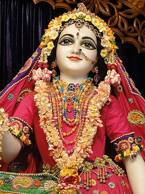 Beautifully adorned Hindu goddess statue wearing vibrant pink sari, floral garlands, and traditional jewelry HD phone wallpaper