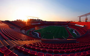 Morumbi Stadium Interior at Golden Hour with Red Seating and Green Pitch HD wallpaper
