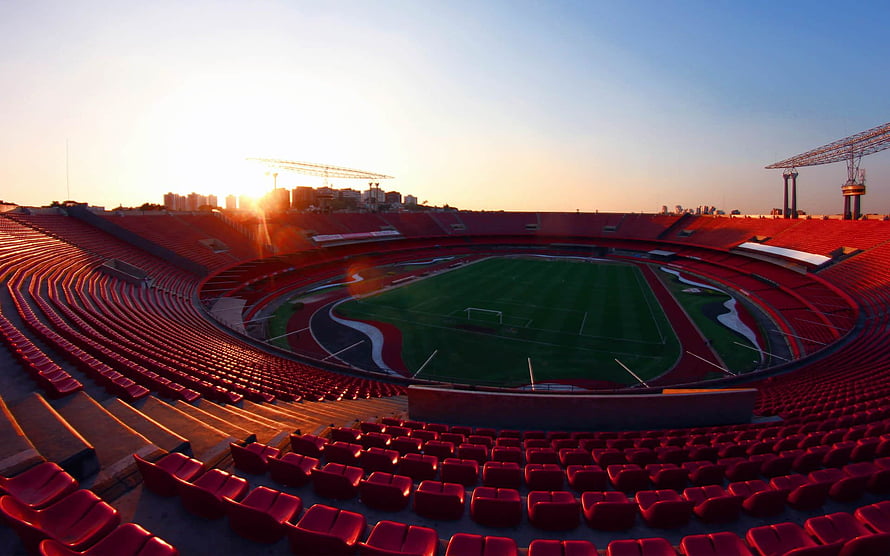Morumbi Stadium Interior at Golden Hour with Red Seating and Green Pitch HD wallpaper