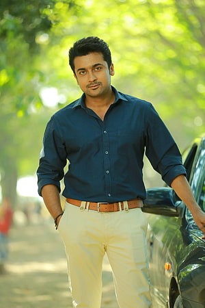 Muhsin Kakkathara in a navy shirt and cream trousers standing beside a car in a sunlit park HD phone wallpaper